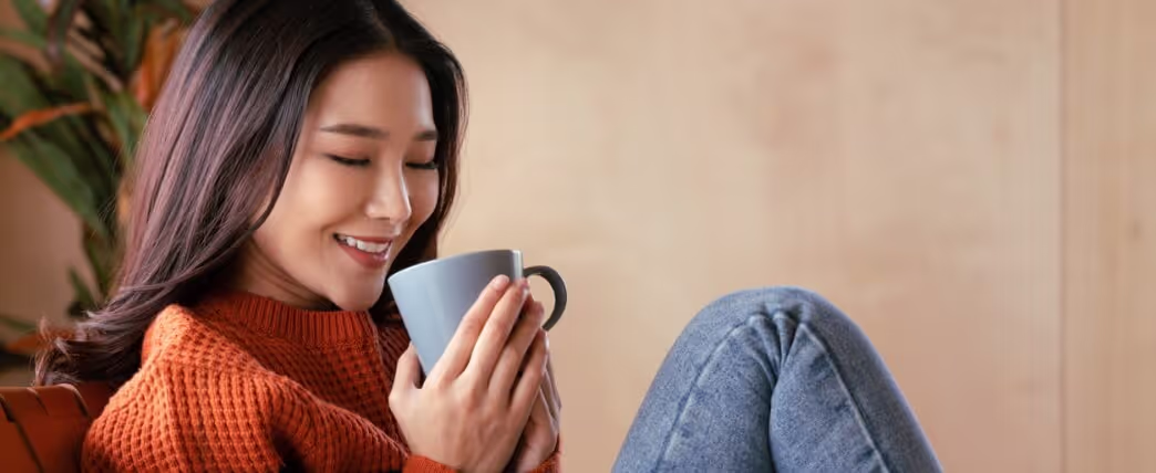 Mulher relaxando com uma xícara de chá para baixar os níveis de cortisol