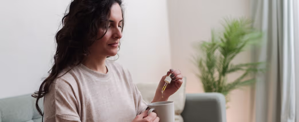 Woman adding cbd oil to tea to help with sleep