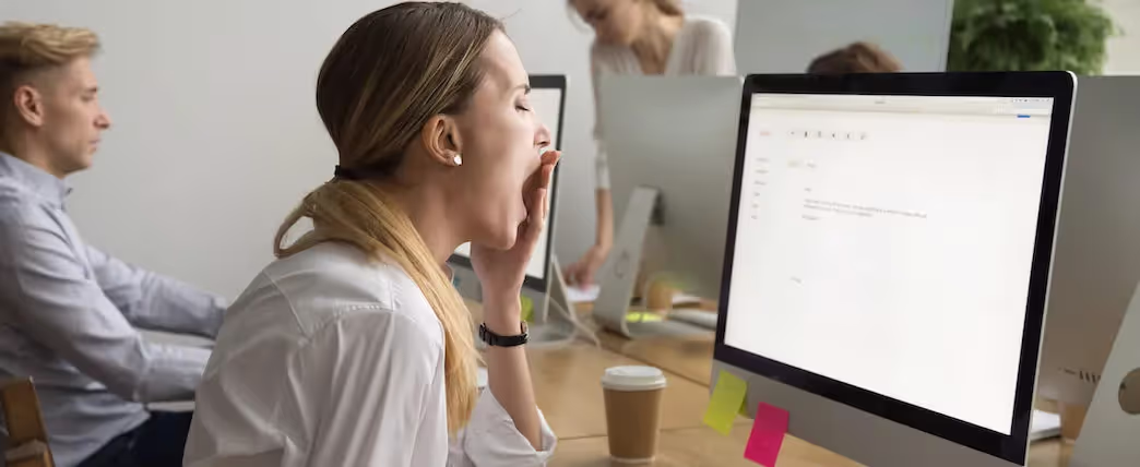 Mujer en el trabajo frente a la computadora bostezando y con mucho sueño por más que duerma