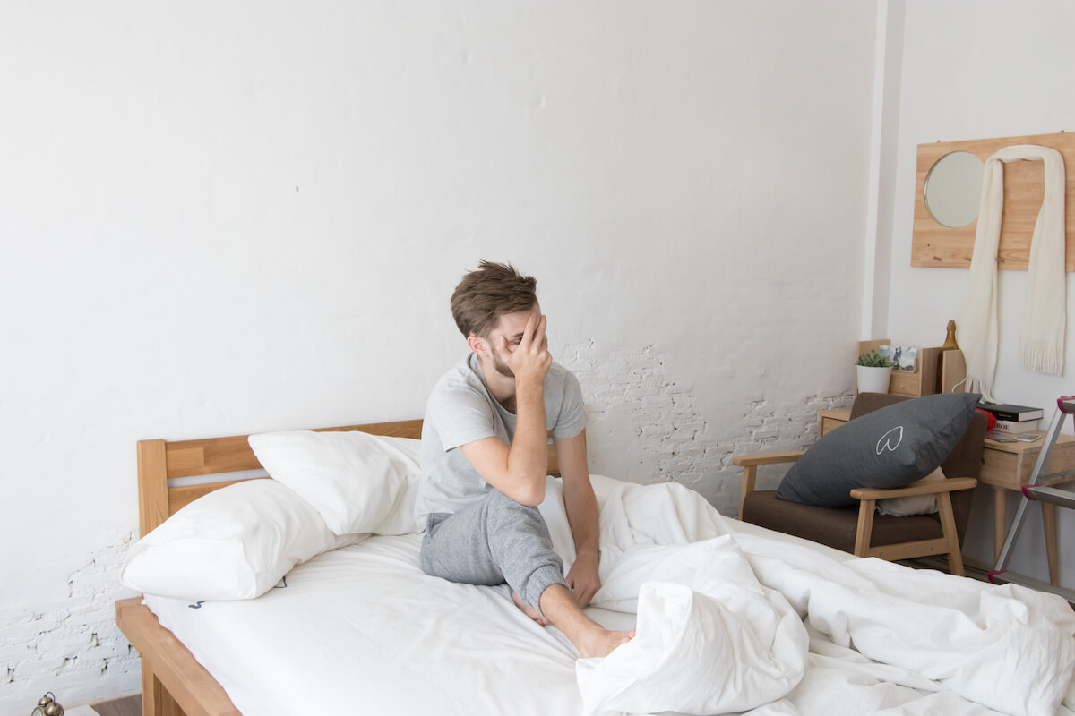 Drinking water before bed: man sitting on his bed, covering his face