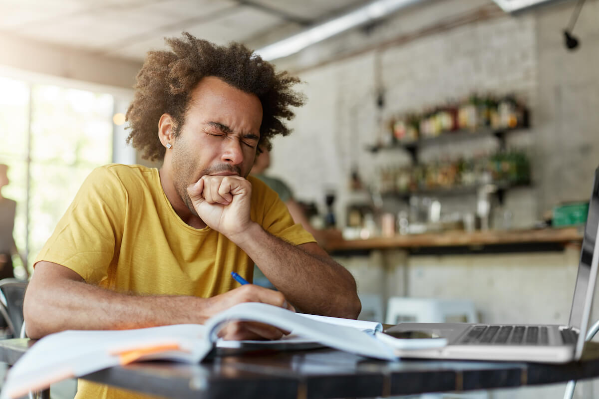 how long can you go without sleep: Man yawning with his eyes closed while working